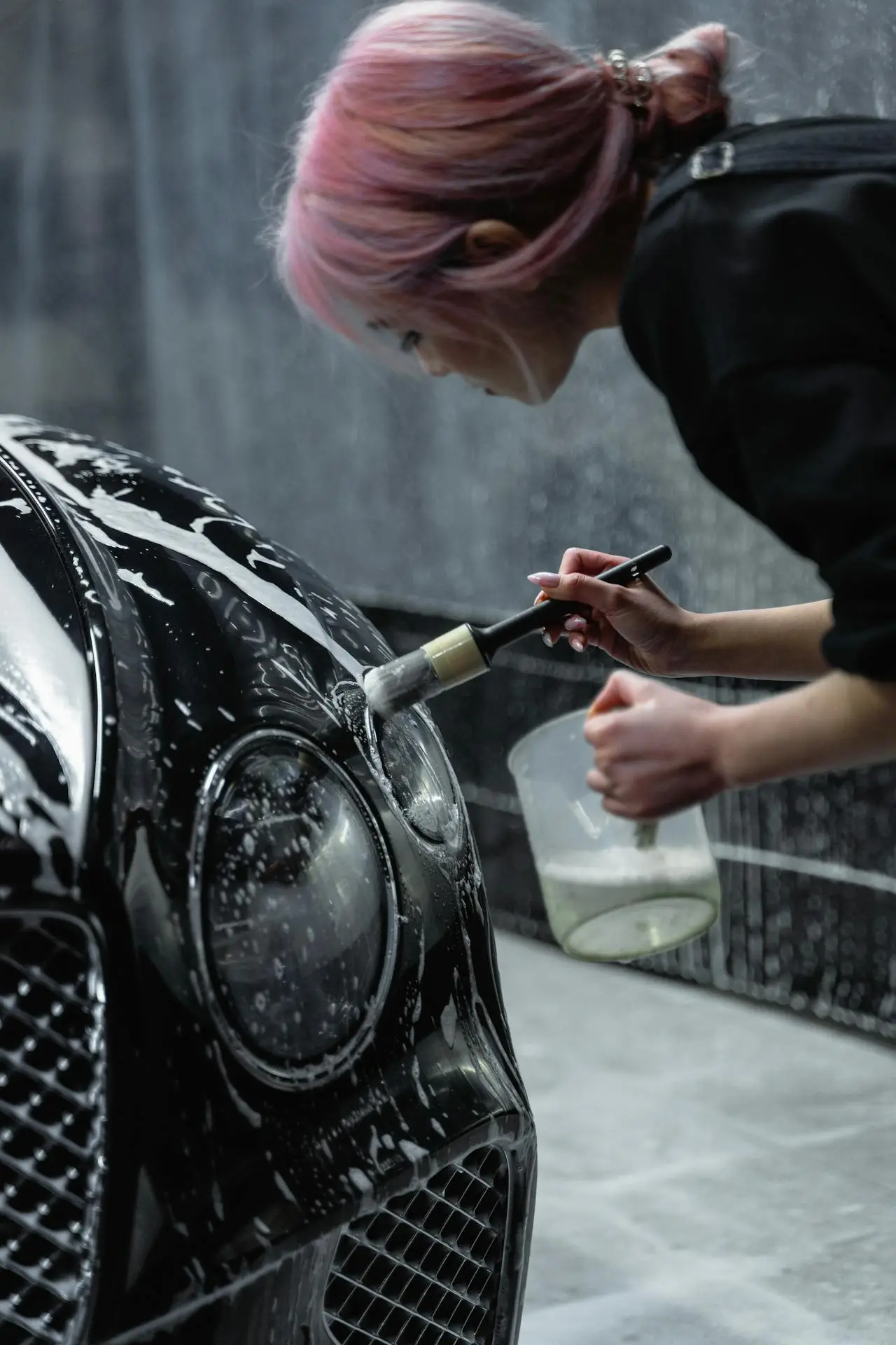 woman detailing a car headlight